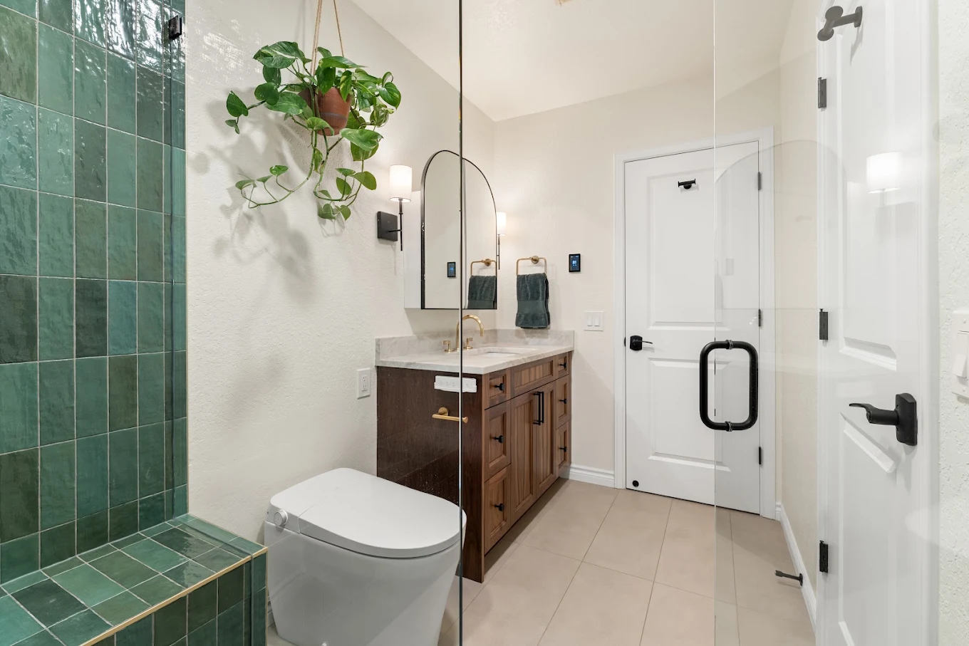 Bothell bathroom with toilet, green-tiled walk-in shower, and furniture style cabinetry 