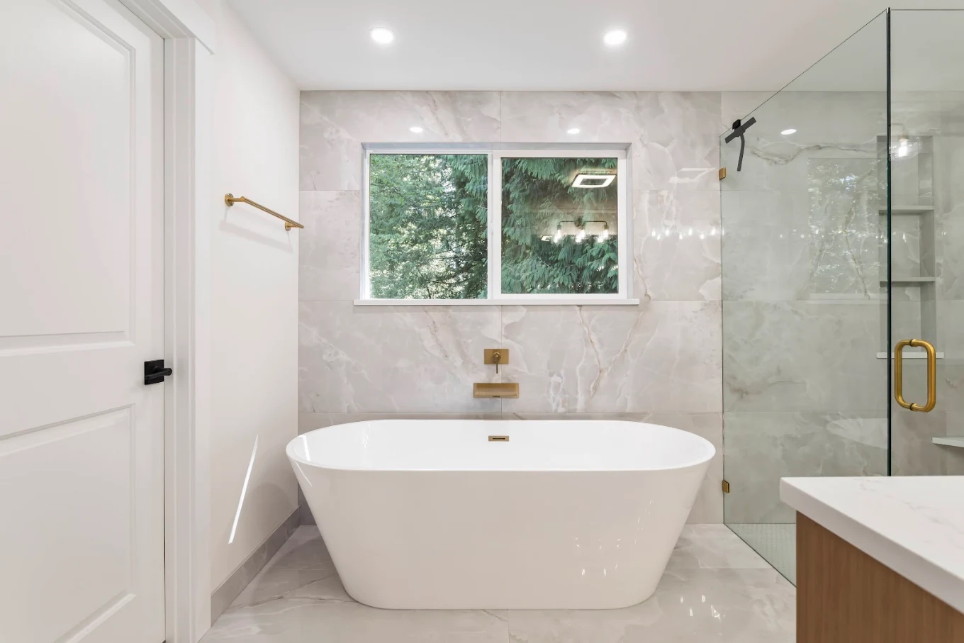 Freestanding tub with brass fixtures and large porcelain tiles in Bothell