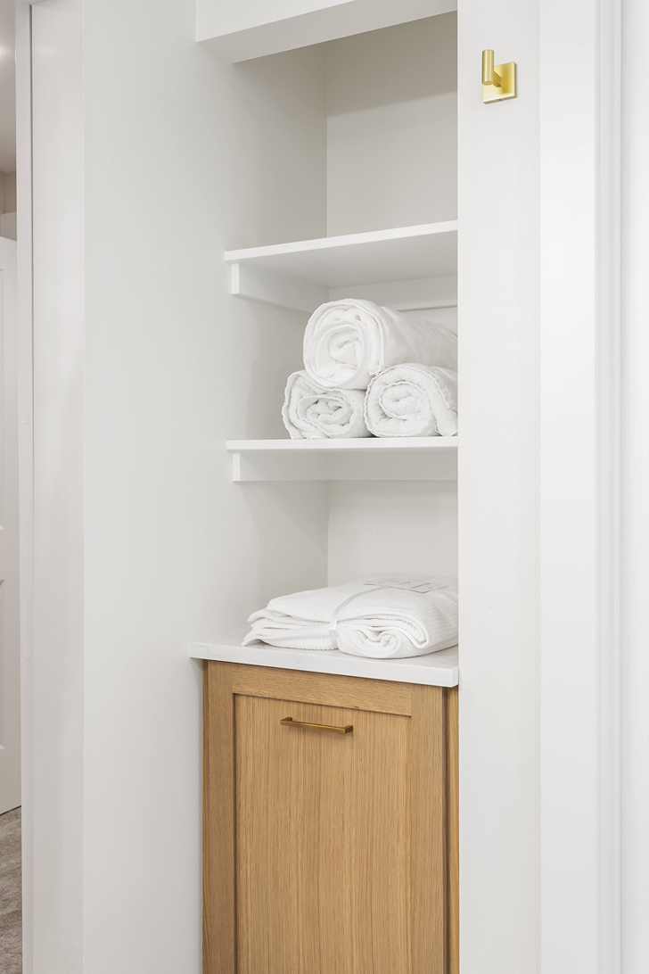 Tall bathroom linen storage tower with adjustable shelves anchored to the wall