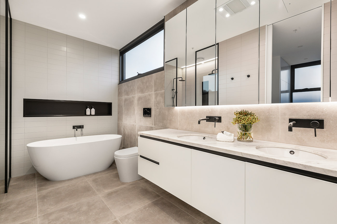 Contemporary bathroom with a freestanding white bathtub, wall-mounted toilet, and a long floating double vanity with integrated sinks