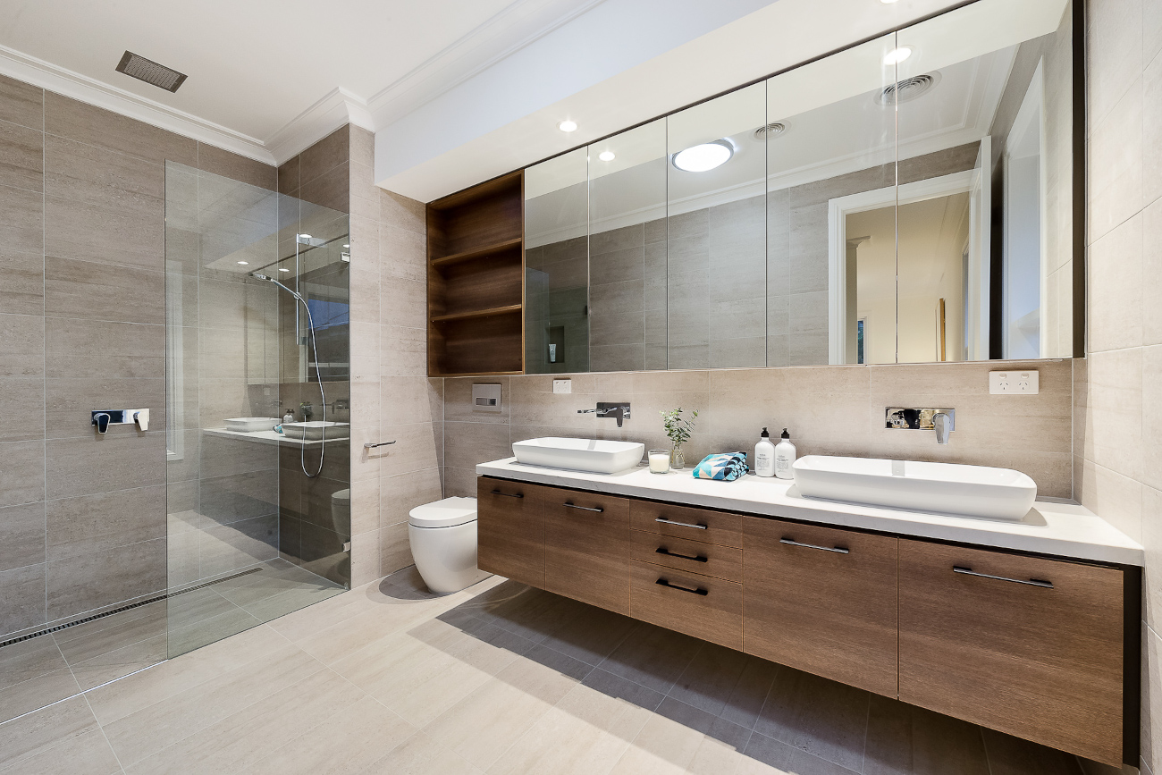 Modern bathroom with beige tiled walls and floor, a glass-enclosed walk-in shower on the left,