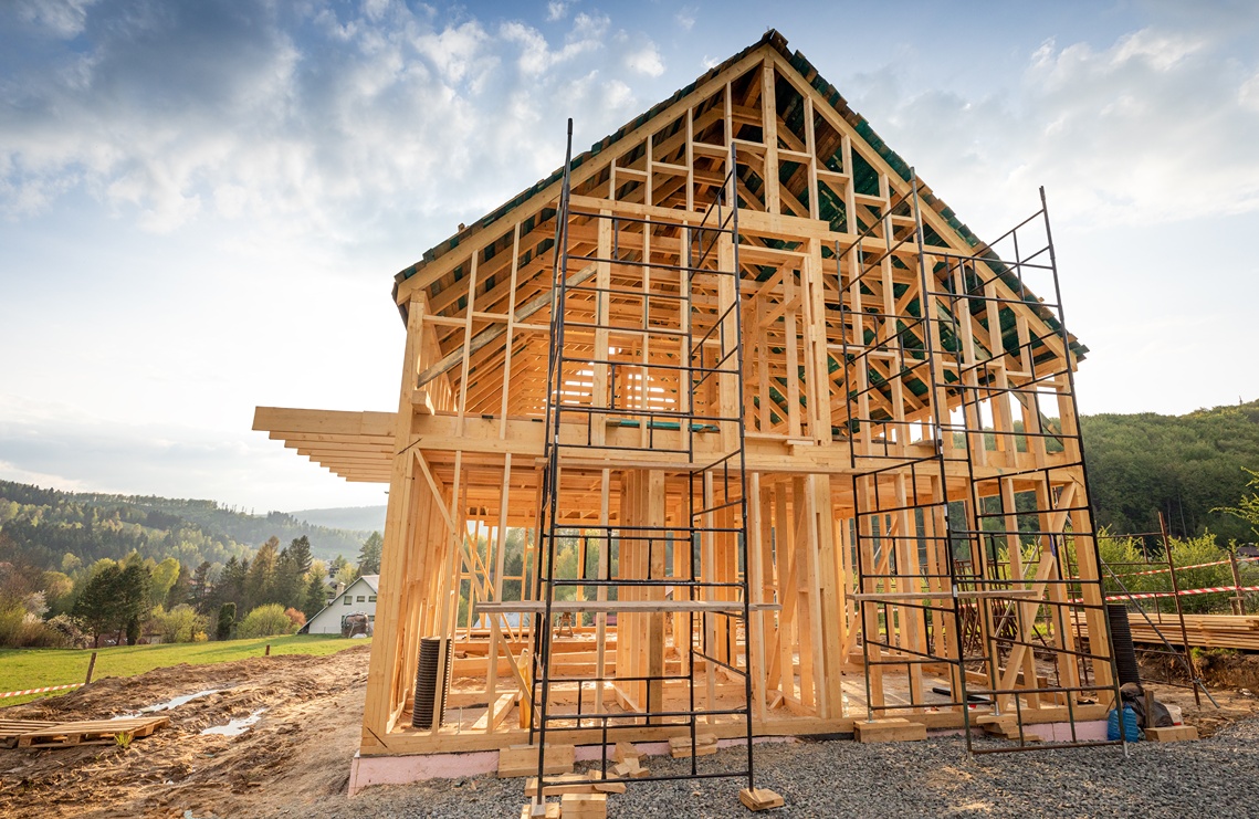 Custom home building process overview showing a newly framed home structure with roof trusses and interior walls