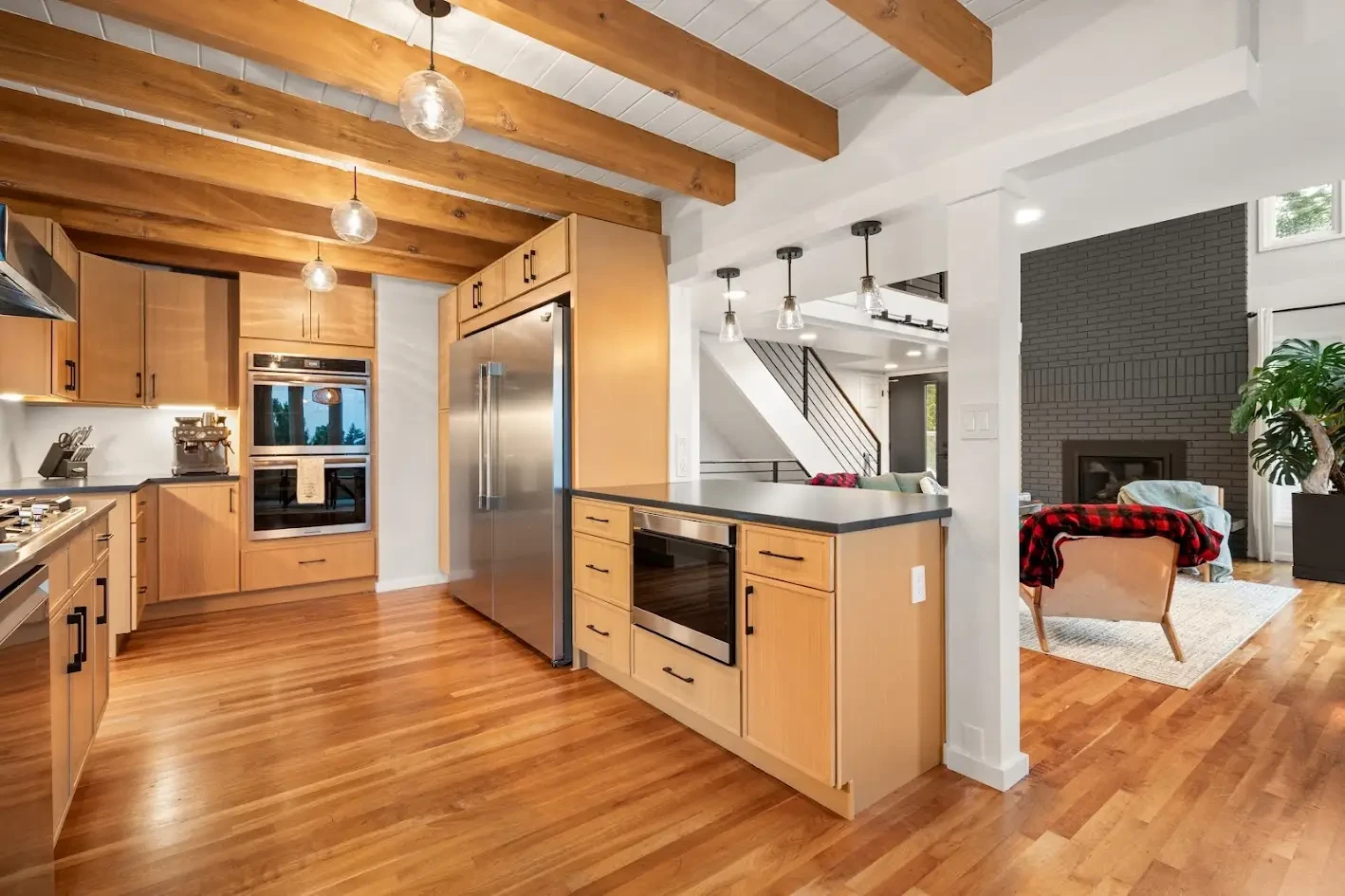 Remodeled kitchen with wood flooring, a wall oven, large refrigerator, and custom cabinetry, built by CraftHaus in the Cottage Lake area