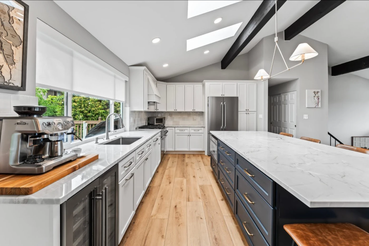 Kitchen island with a marble top, sink, coffee station, and custom cabinetry in a Cottage Lake home