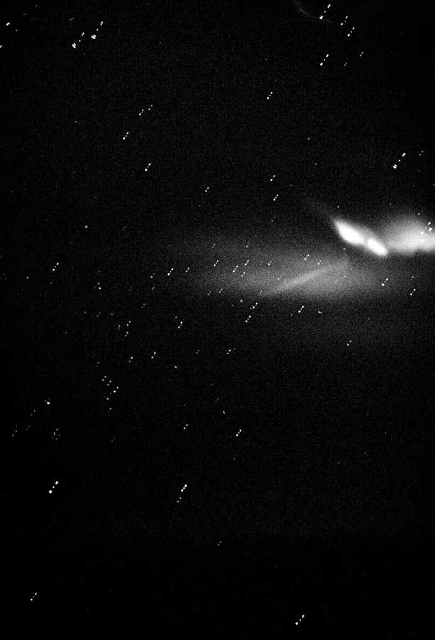 Black and white image of a starry sky with a bright, nebulous cloud formation on the right side.