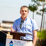 Speaker giving a presentation at a Pure Water event promoting clean water initiatives and sustainable resources.