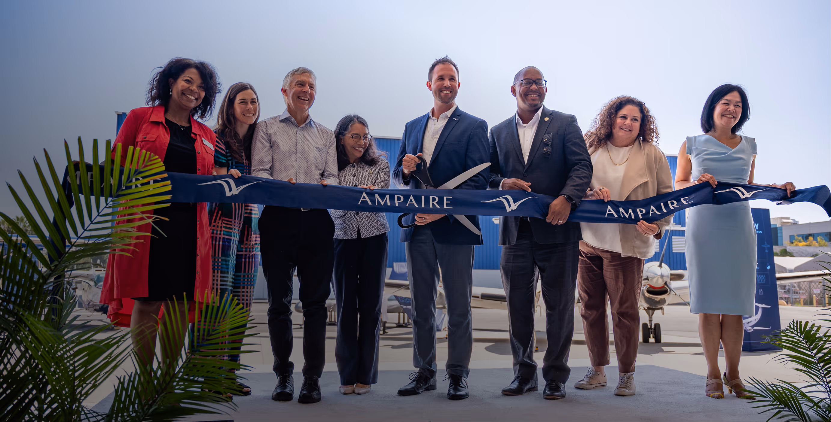 Ampaire team and partners participating in a ribbon-cutting ceremony in front of an aircraft, symbolizing the company’s innovation in sustainable aviation.