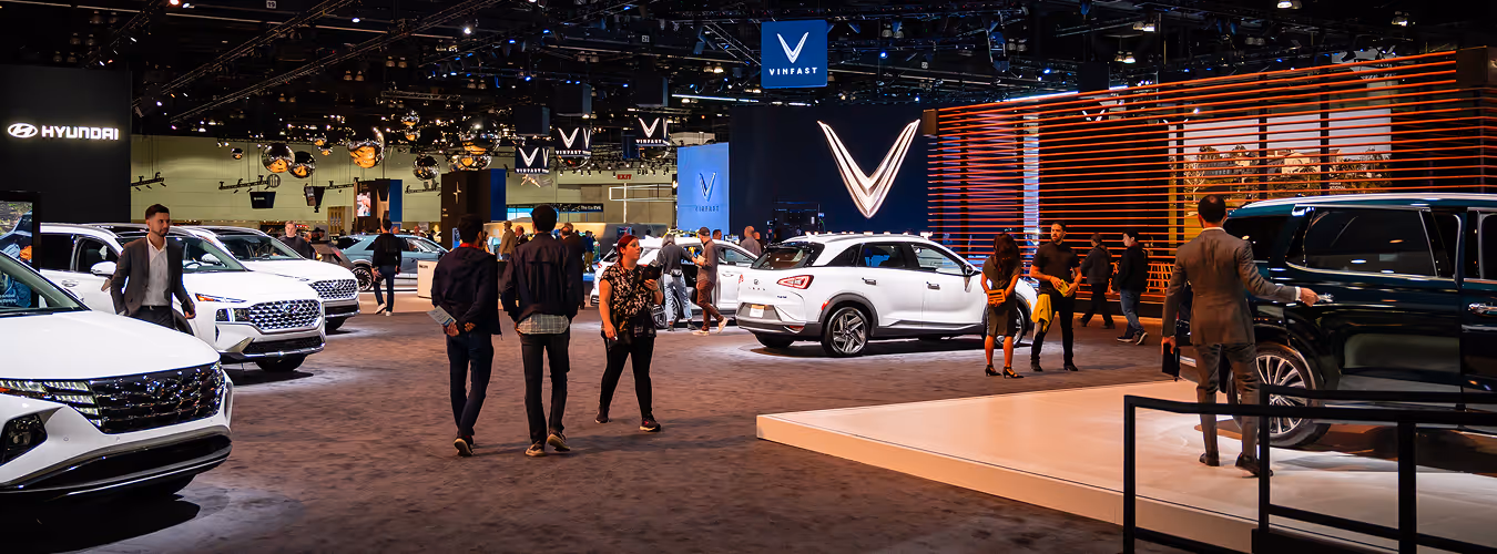 People attending an automotive trade show showcasing modern vehicles and innovative mobility solutions.