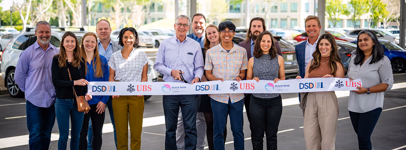 Company team celebrating a partnership ribbon-cutting event, symbolizing collaboration and business growth.