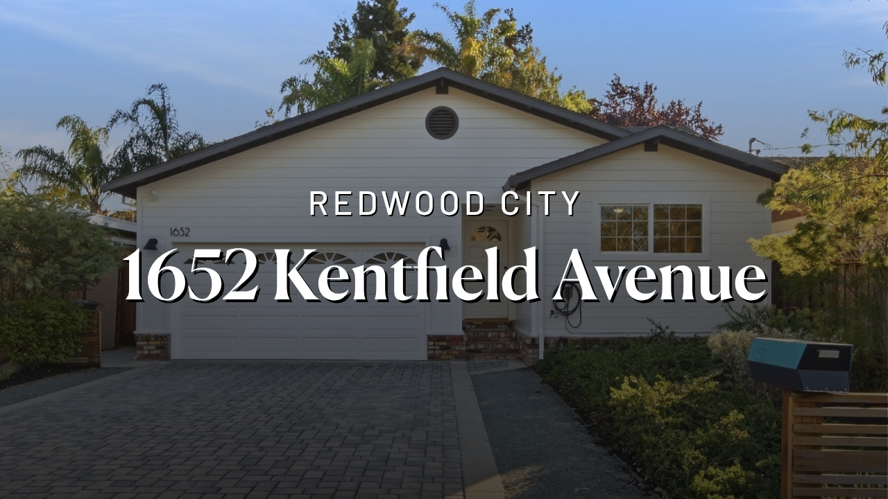 Single-story white house with a gray shingled roof, two-car garage, brick steps to front door, adjacent driveway, and lush greenery in front yard at 1652 Kentfield Avenue, Redwood City.