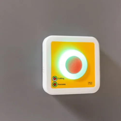 Draadloze BHV-noodknop aan de muur met verlichte ring, gekoppeld aan de BHV App voor het snel alarmeren van hulp bij noodsituaties.