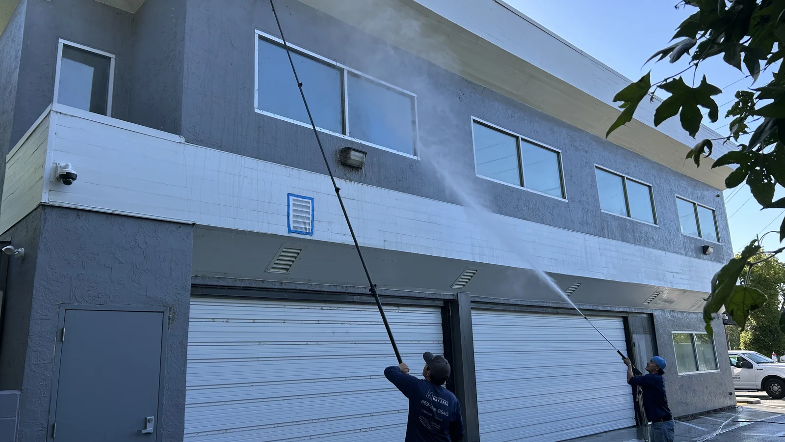 Technician cleaning ground-floor commercial windows with a water-fed pole