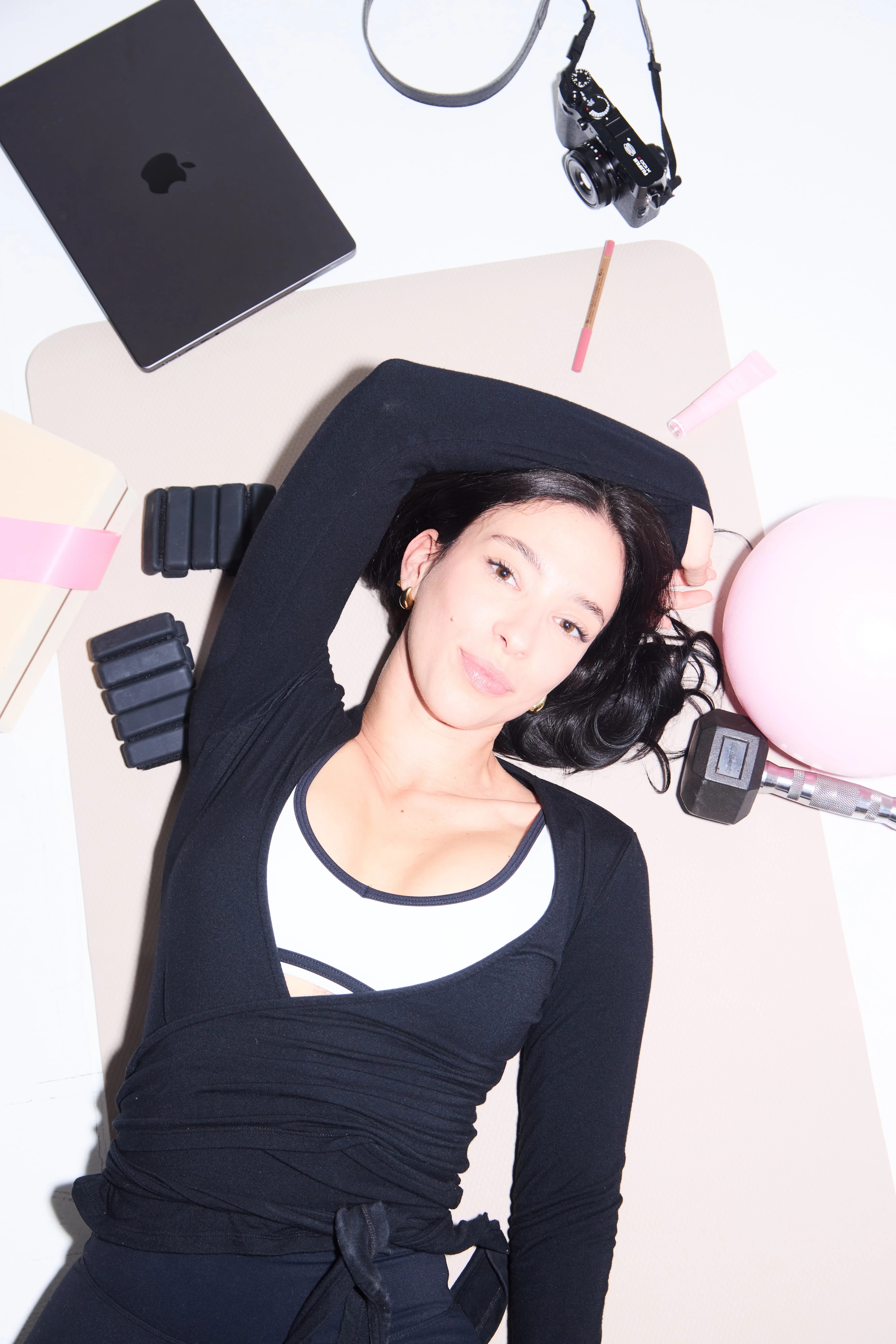 Three women in black and white athletic wear posing with a gray exercise ball in a bright studio.