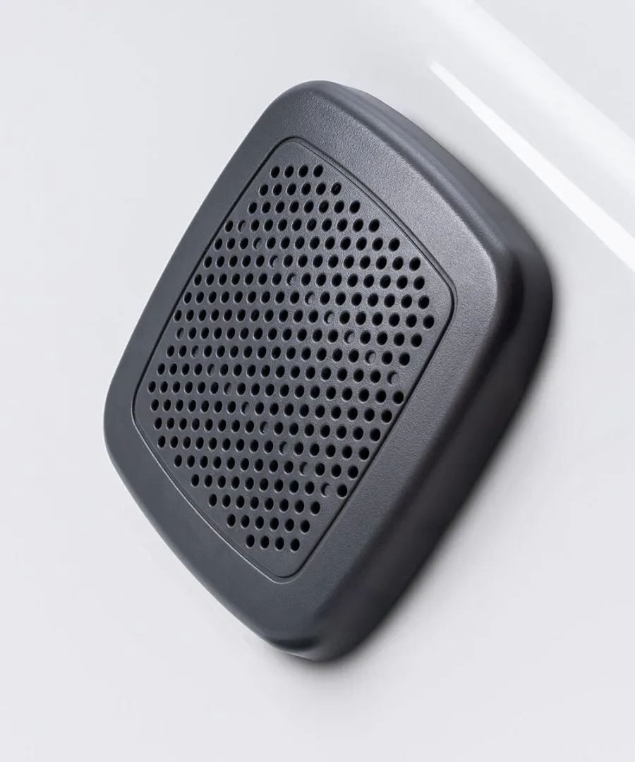 Grauer quadratischer Lautsprecher mit gelochter Oberfläche auf weißem Hintergrund