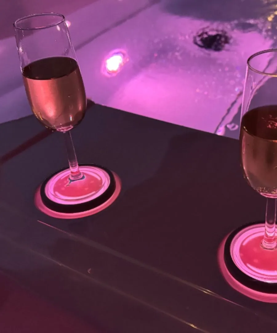 Zwei Weingläser mit rosafarbenem Licht auf rosa Untersetzer