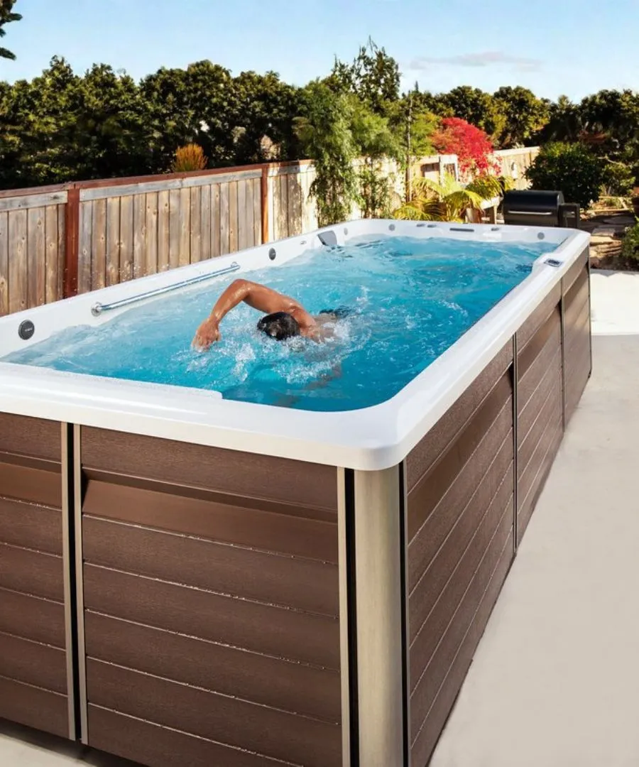 Schwimmer trainiert im Außenpool mit Holzzaun und Garten im Hintergrund