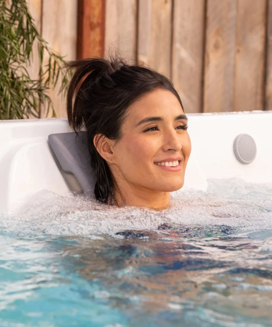 Lächelnde Person entspannt im Whirlpool mit Seifenblasen und Holzwand