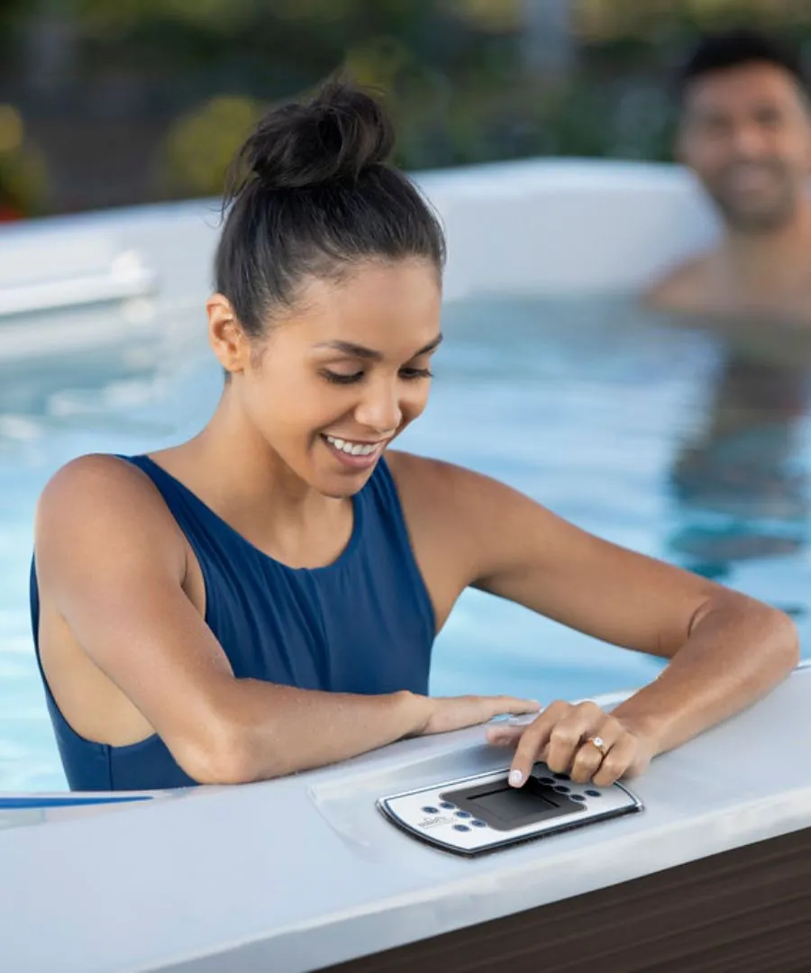 Frau lächelt und bedient Steuerungspanel im Whirlpool