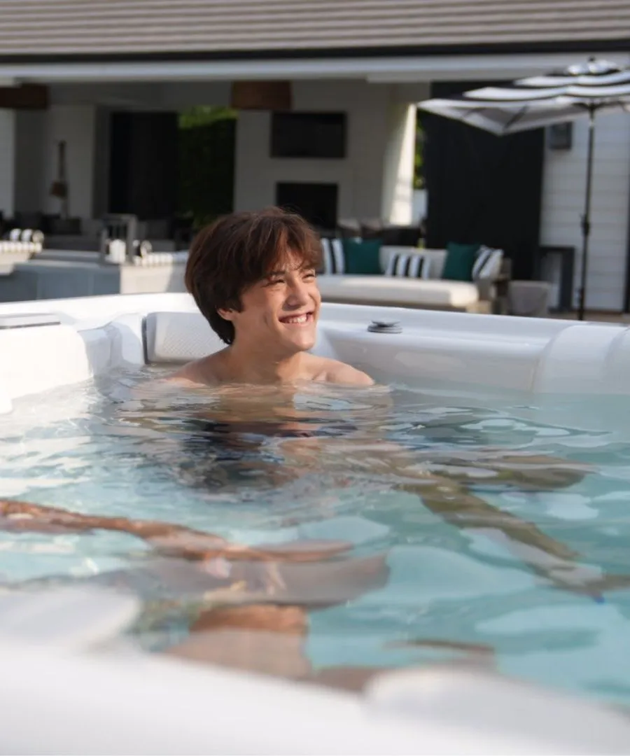 Person lächelt entspannt im Whirlpool mit moderner Terrasse im Hintergrund