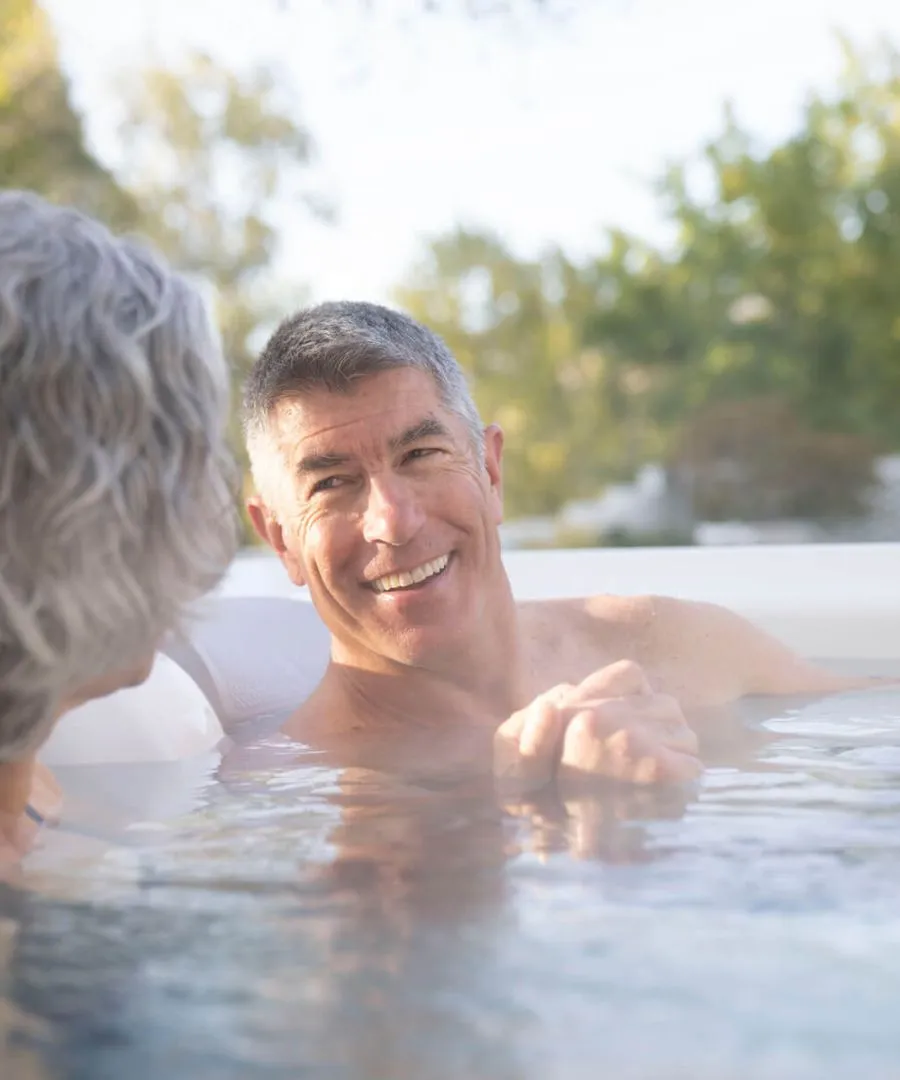 Lächelnder älterer Mann entspannt im Außenpool mit Wasserspiegelung