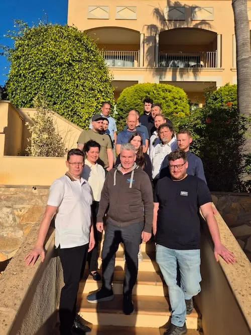 Gruppe von Männern, die Treppe in sonniger Umgebung mit Palmen hinuntergehen