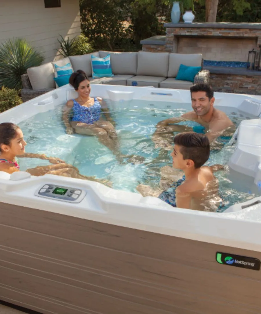 Familie entspannt im Whirlpool mit Terrasse und Garten im Hintergrund