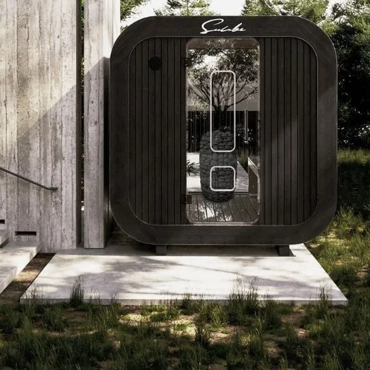 Suncube Outdoor-Sauna als schwarzer Kubus mit Glasfront in einem modernen Garten