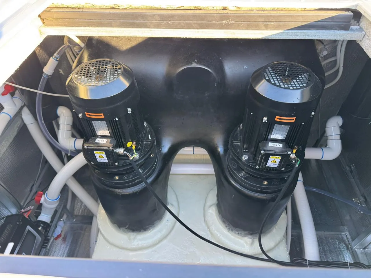 Zwei leistungsstarke Pumpen im Inneren eines Whirlpools, umgeben von Rohren und technischen Komponenten.