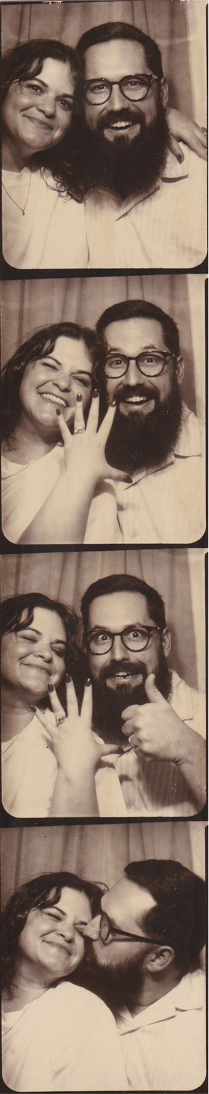 Four black and white photo booth portraits of a smiling couple; the woman shows an engagement ring and the man gives a thumbs up and kisses her on the cheek.