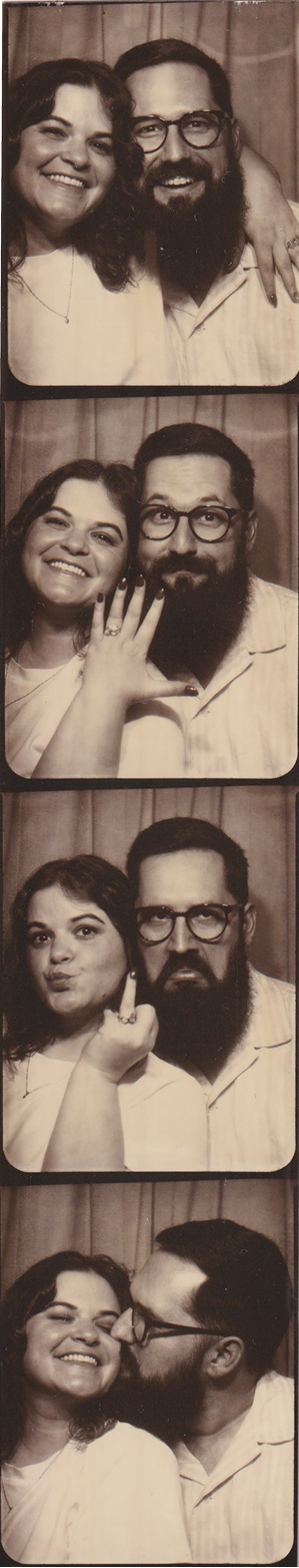 Series of four sepia-toned photo booth pictures of a smiling couple showing an engagement ring and sharing a kiss.