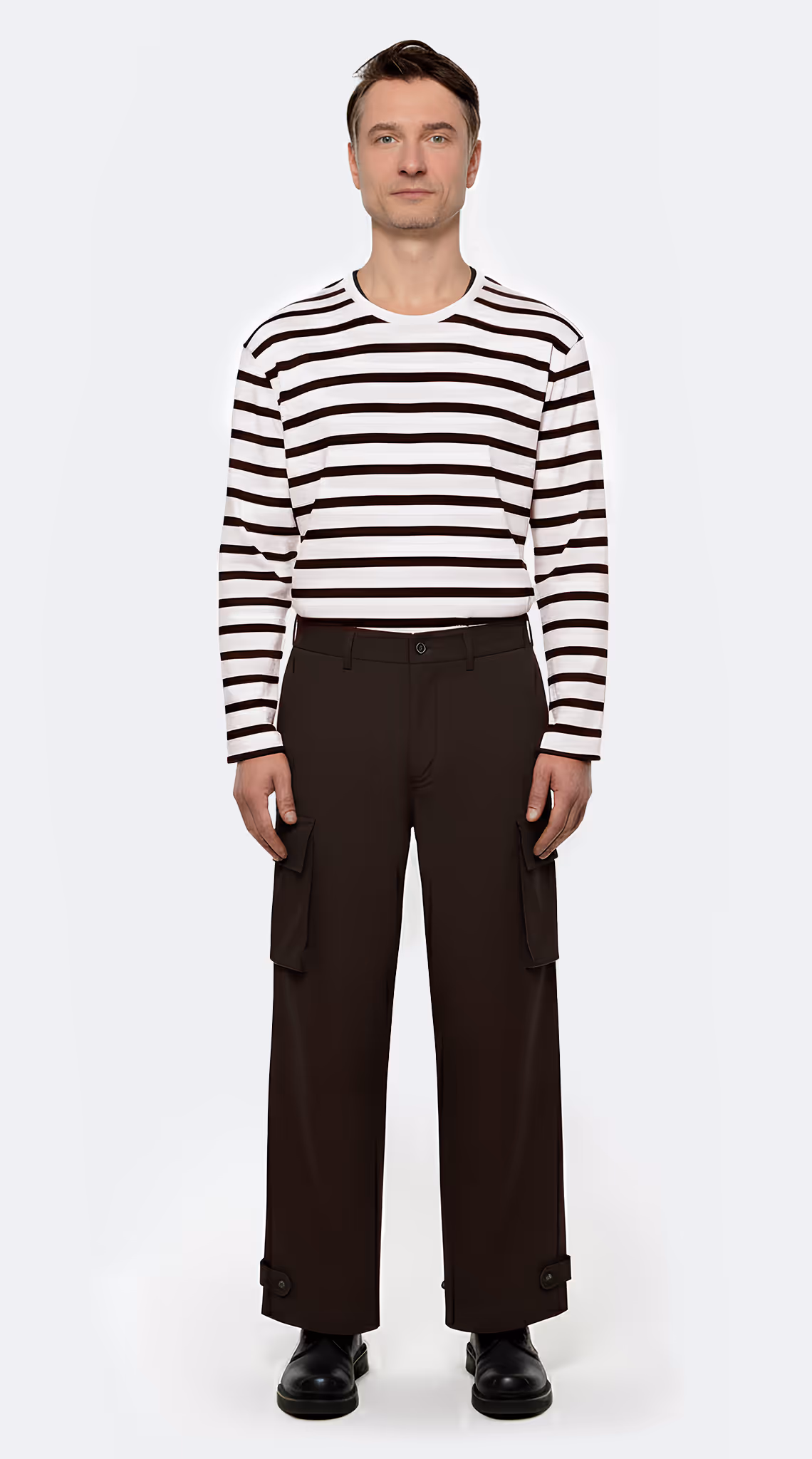 Man standing against plain background wearing a white long-sleeve shirt with black horizontal stripes, black cargo pants, and black shoes.