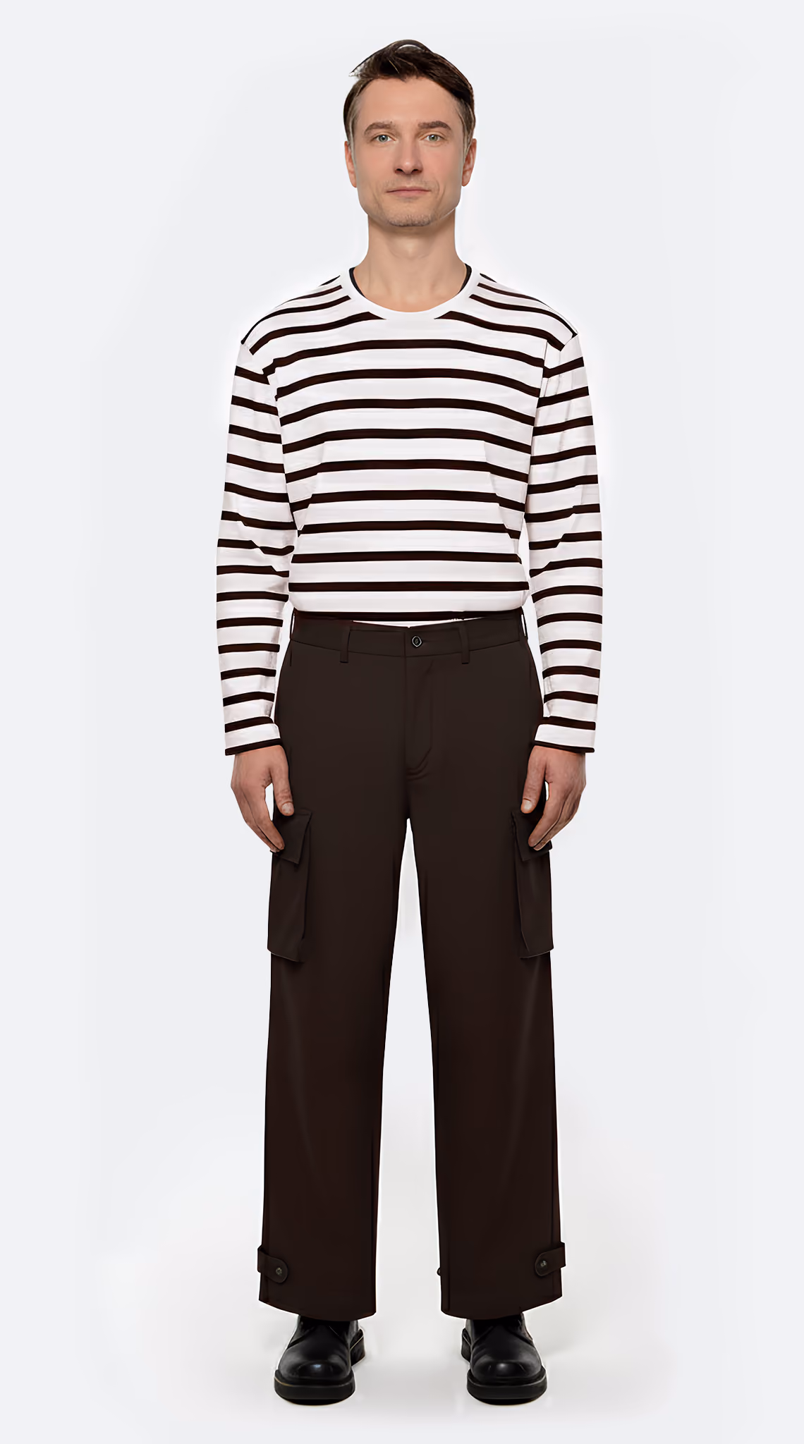 Man standing against plain background wearing a white long-sleeve shirt with black horizontal stripes, black cargo pants, and black shoes.
