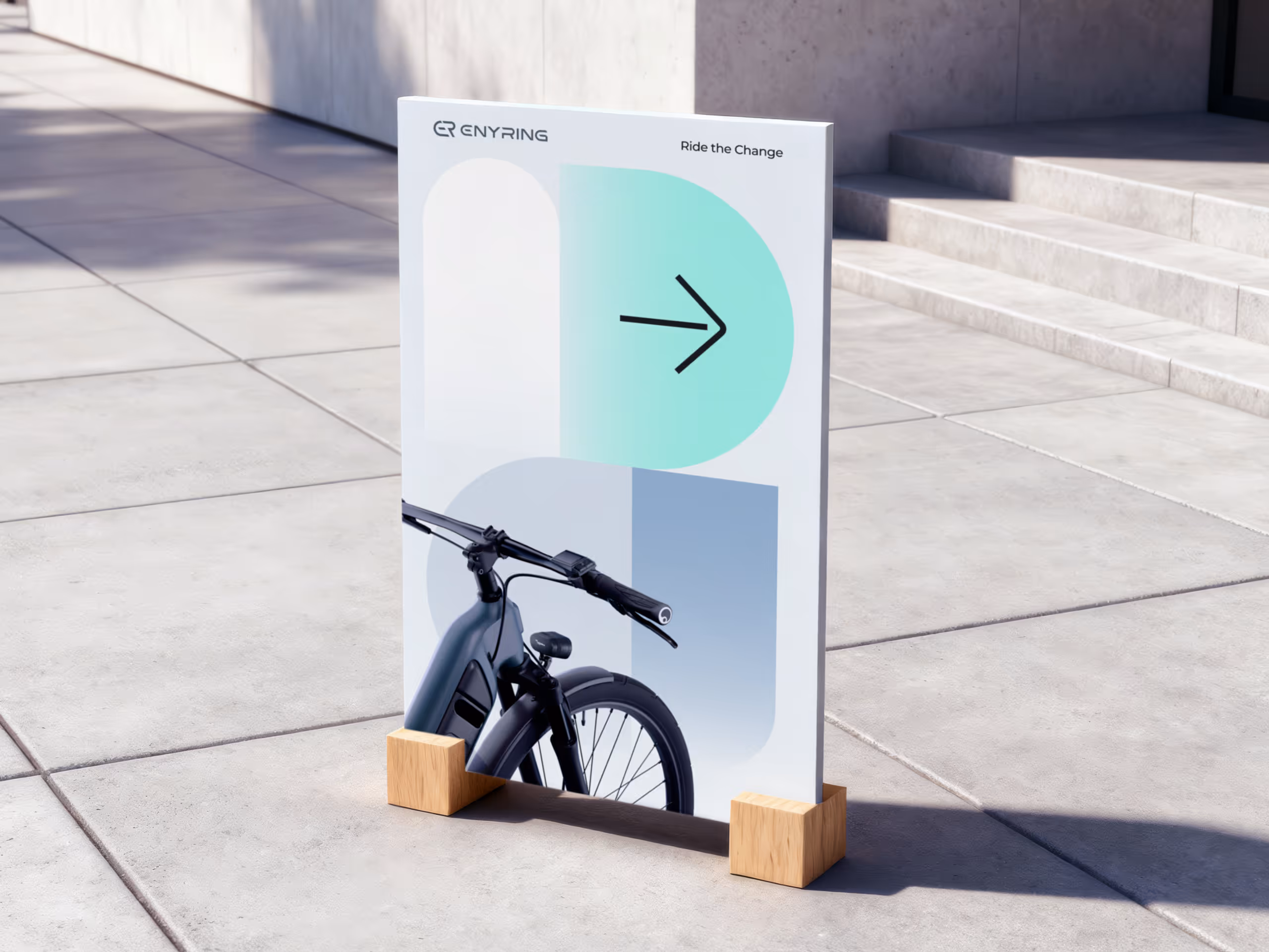Outdoor sign on pavement displaying a bike handlebar and a right arrow with the text 'ENYRING' and 'Ride the Change'.