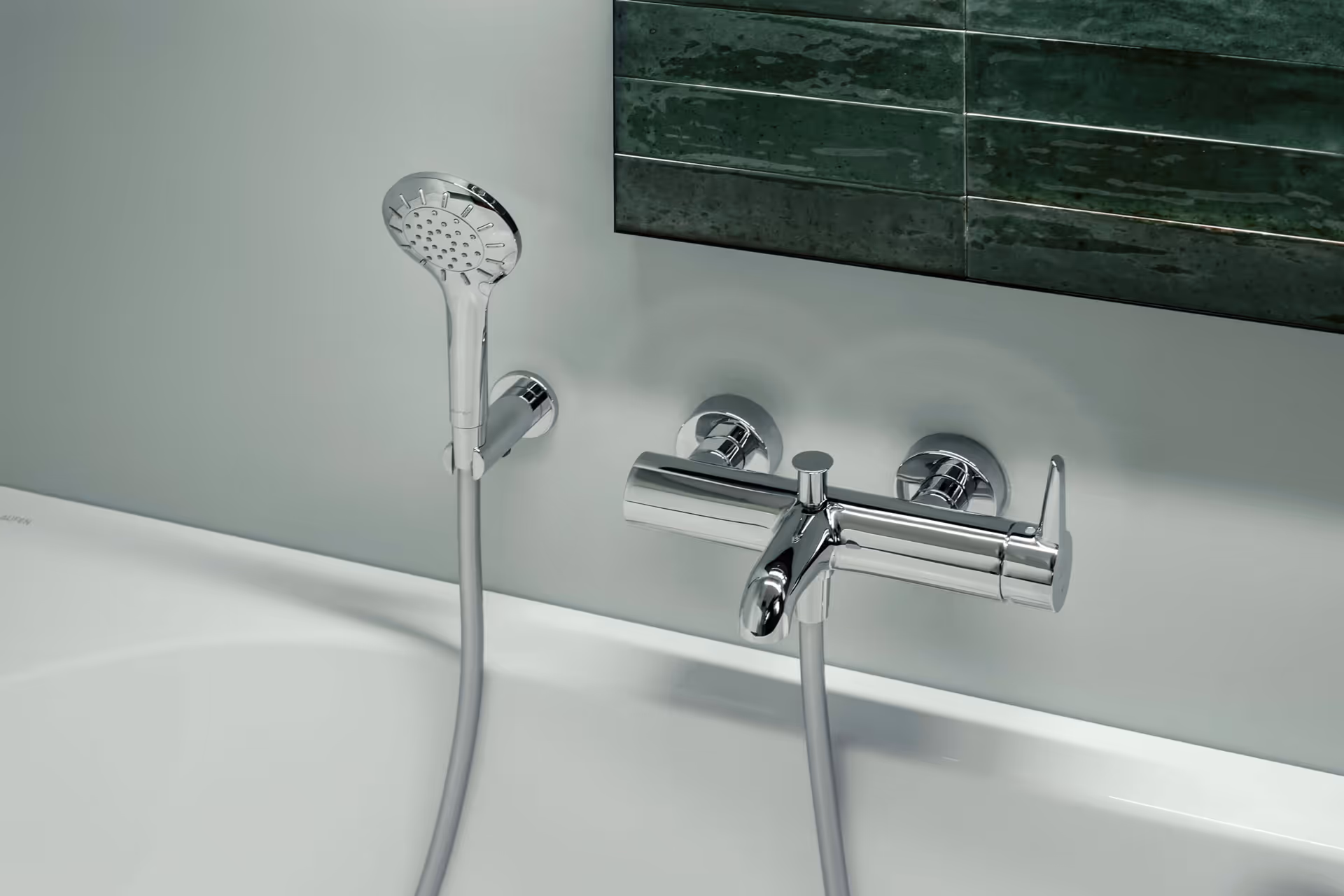 Modern chrome bathtub faucet with attached handheld showerhead mounted on a white wall above a white bathtub.
