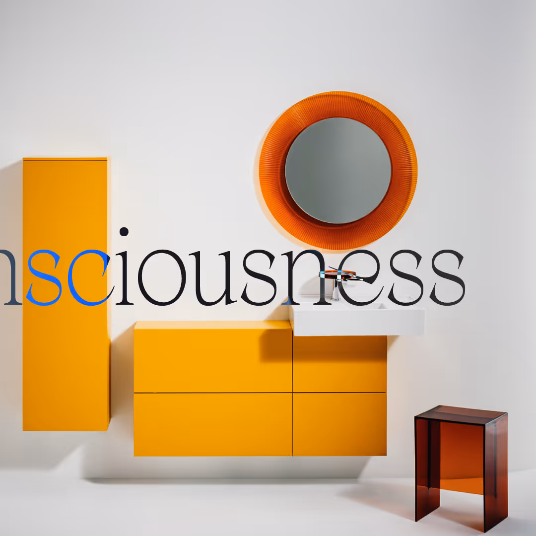 Modern bathroom setup with bright orange wall cabinets, a white sink with an orange circular mirror above, and a translucent amber-colored stool on the right.