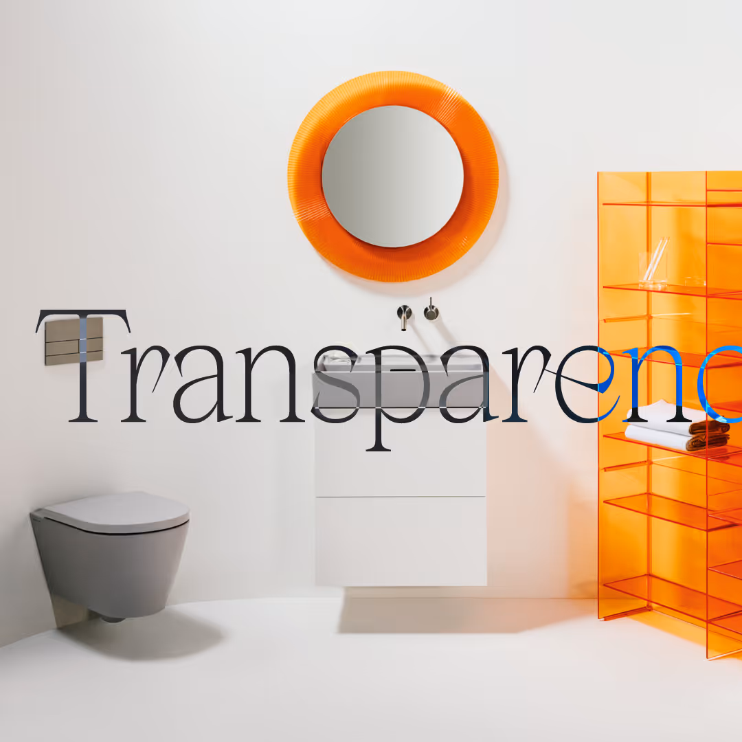 Minimalist bathroom with a wall-mounted gray toilet, white floating sink cabinet, round orange-framed mirror, and transparent orange shelving unit.