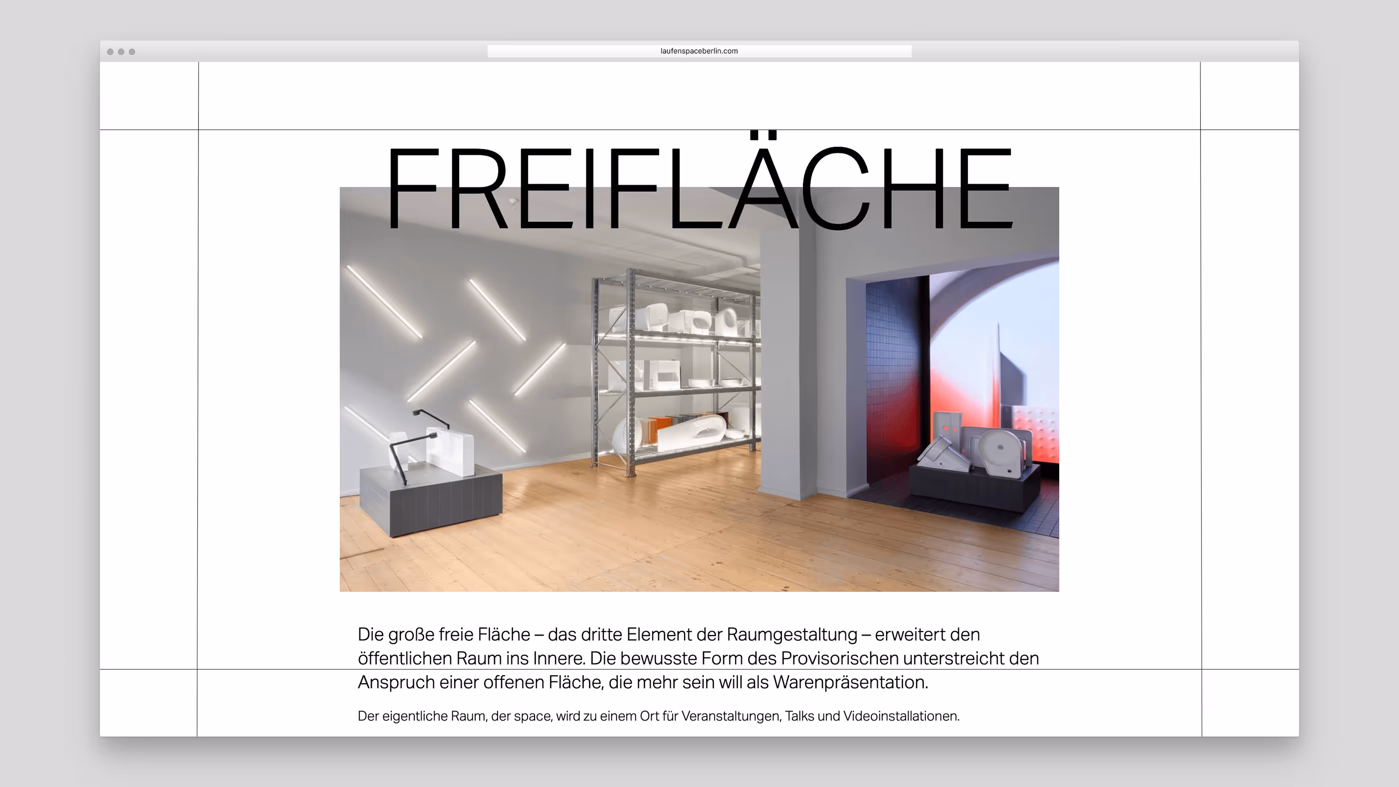 Modern gallery space with wooden floor, illuminated wall lights, metal shelving holding white bathroom fixtures, and a window with red and purple gradient light.