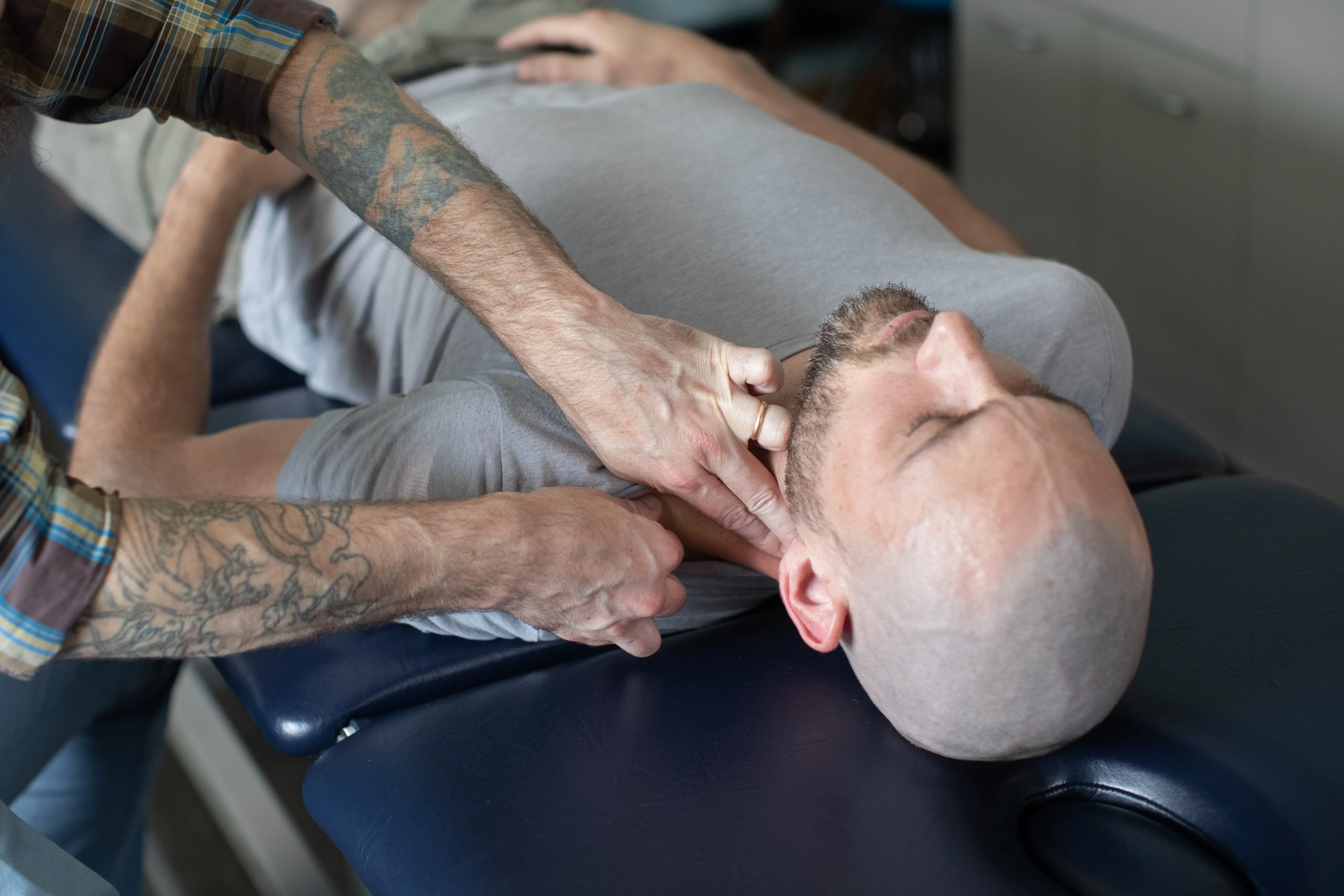 Close-up of Dr. Joseph McCue's hands performing a manual neck adjustment on a patient