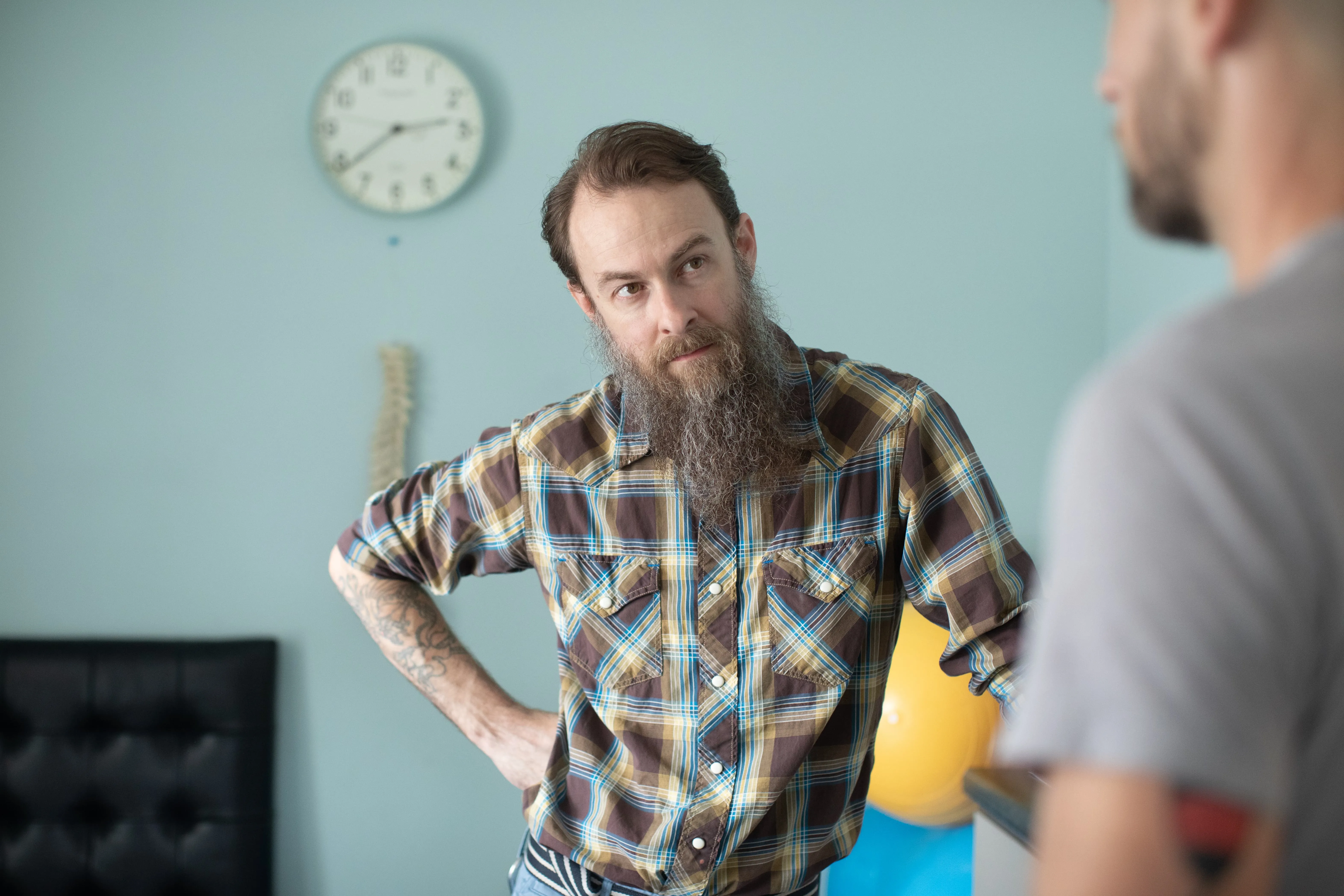 Dr. Joseph McCue speaking with a patient during a consultation, with a spine model visible in the background
