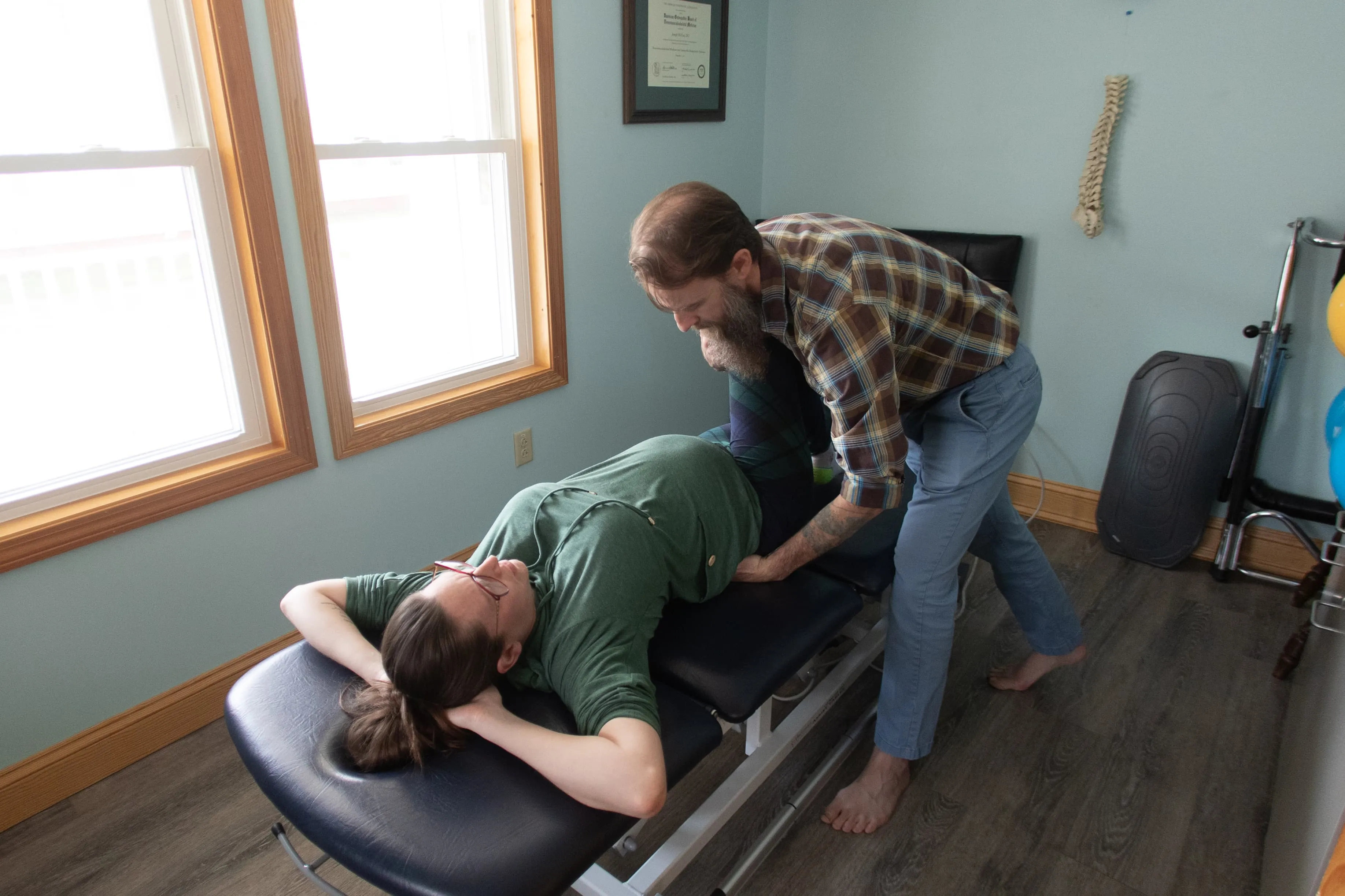 Dr. Joseph McCue performing an osteopathic spinal adjustment on a patient lying on a treatment table