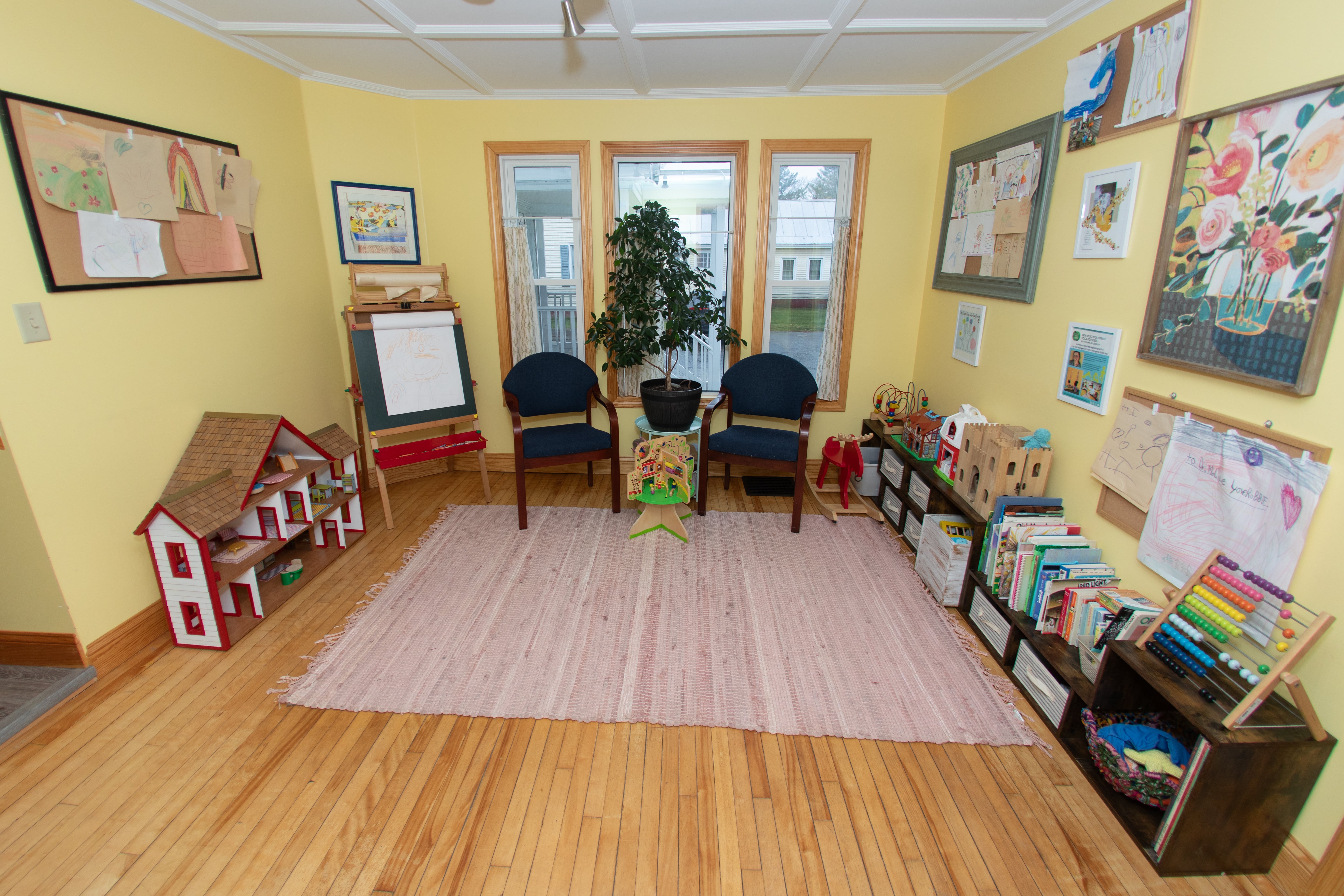 Family-friendly waiting area with children's toys, books, an art easel, and a dollhouse