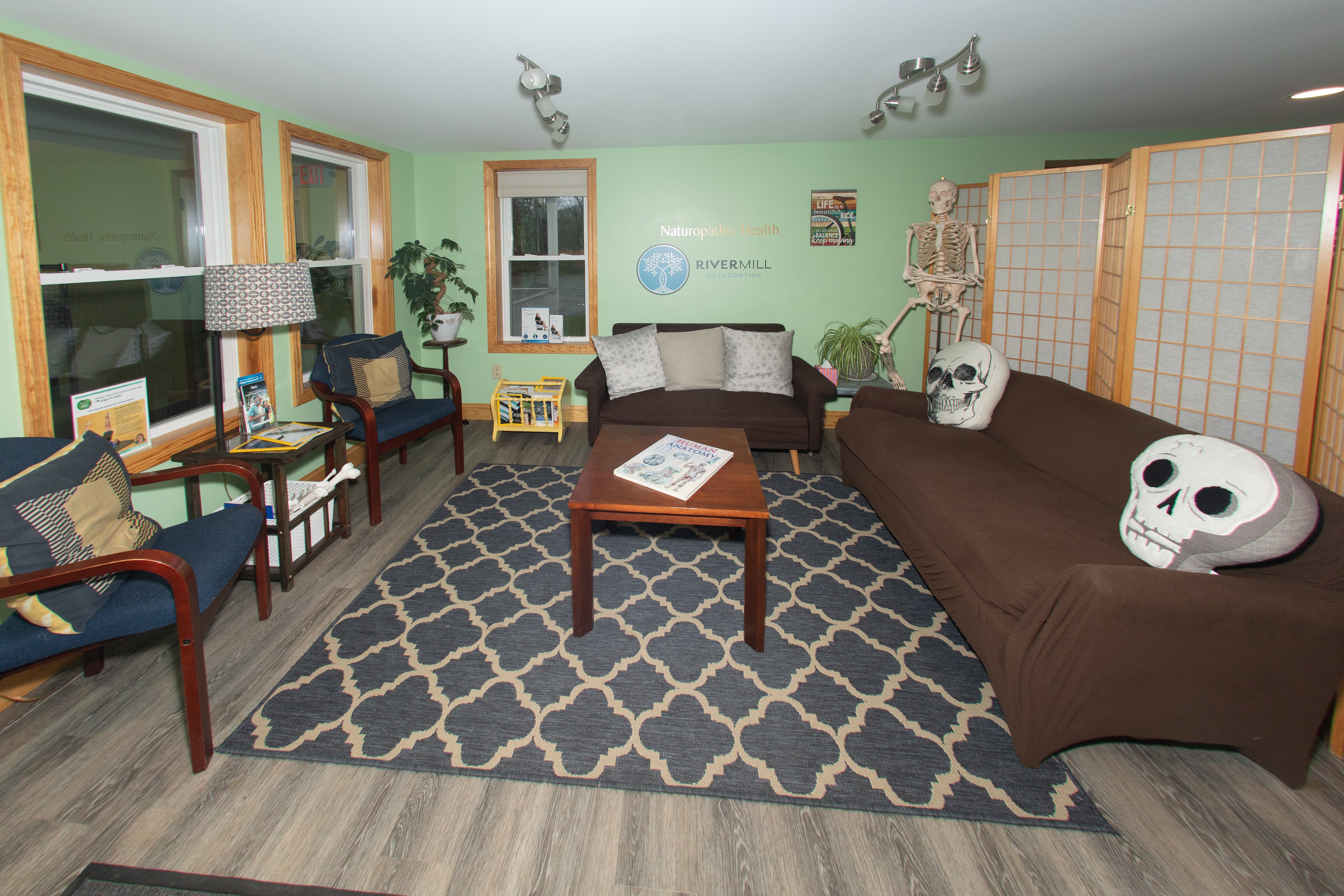 River Mill Osteopathic waiting room with comfortable seating, anatomy references, and the practice logo on the wall