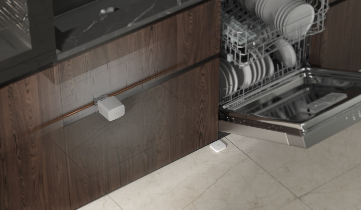 Ajax water leak detector installed near a kitchen dishwasher and plumbing area to help alert homeowners about water leak risks as part of a smart security system.