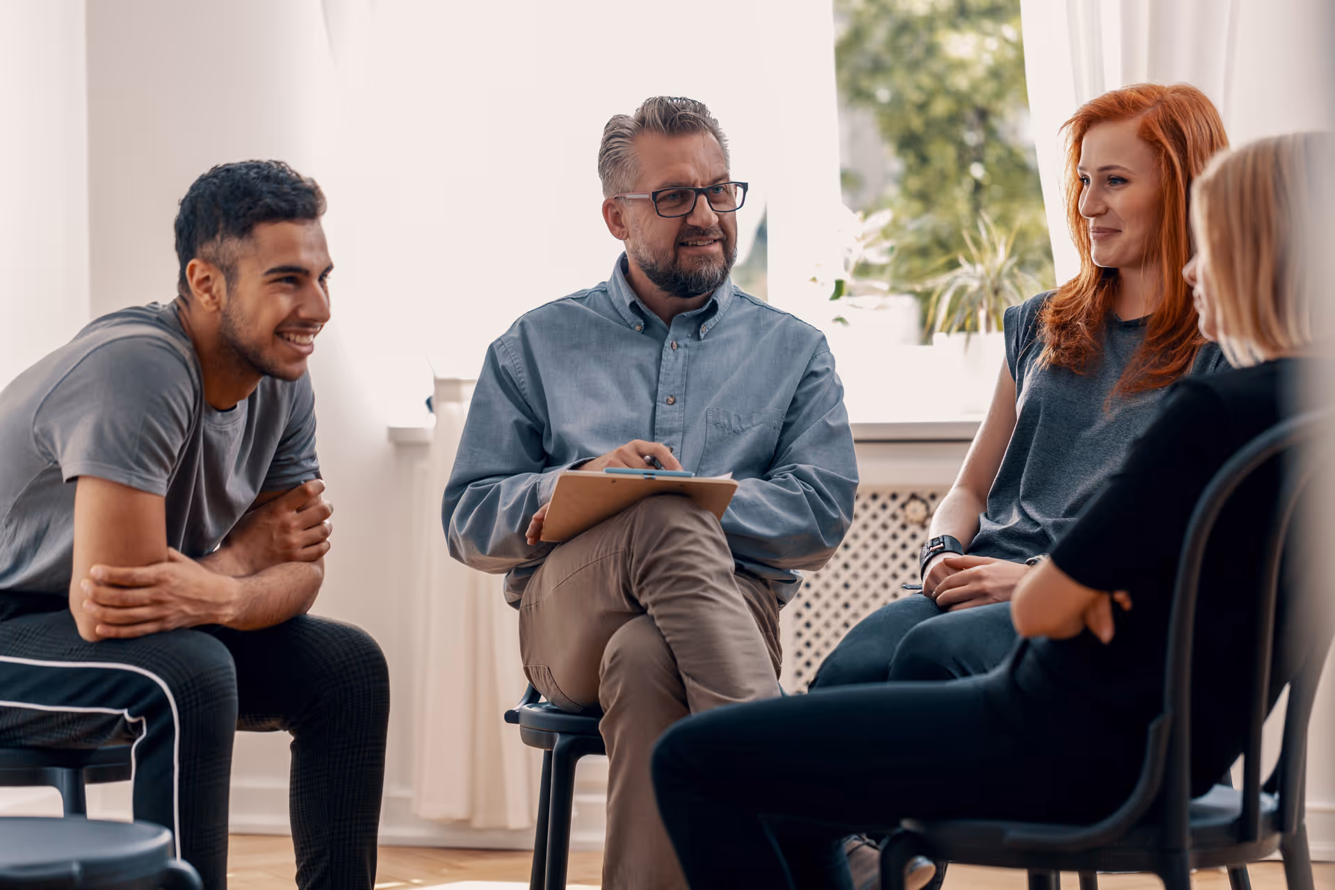 Four people sitting in a circle having a friendly group discussion in a bright room.