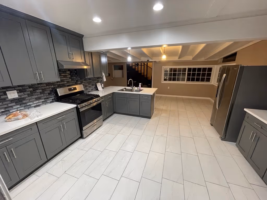 Modern kitchen with gray cabinets, stainless steel appliances, white countertops, and white tile floor.