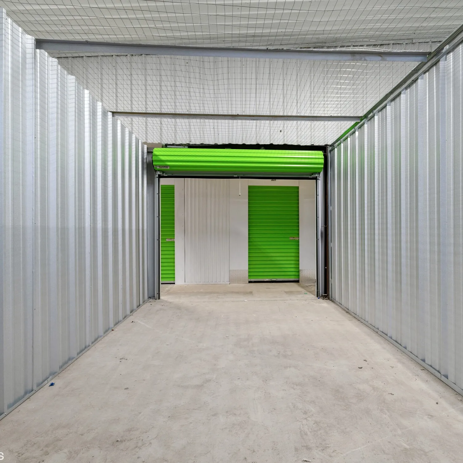 Lookign from the inside to the outside of a self storage unit with a green roll up door