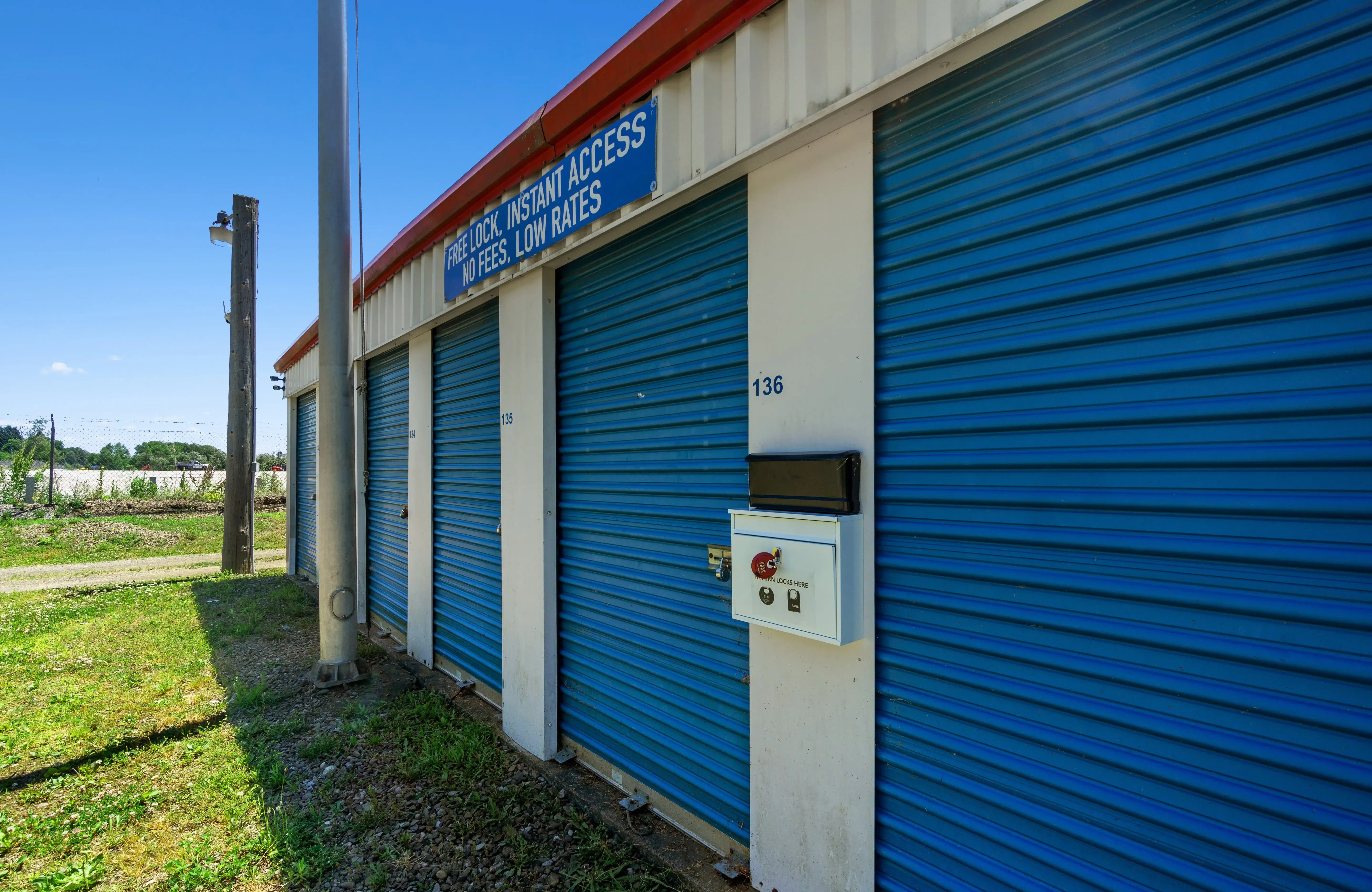 side view of four self storage units with blue roll up doors