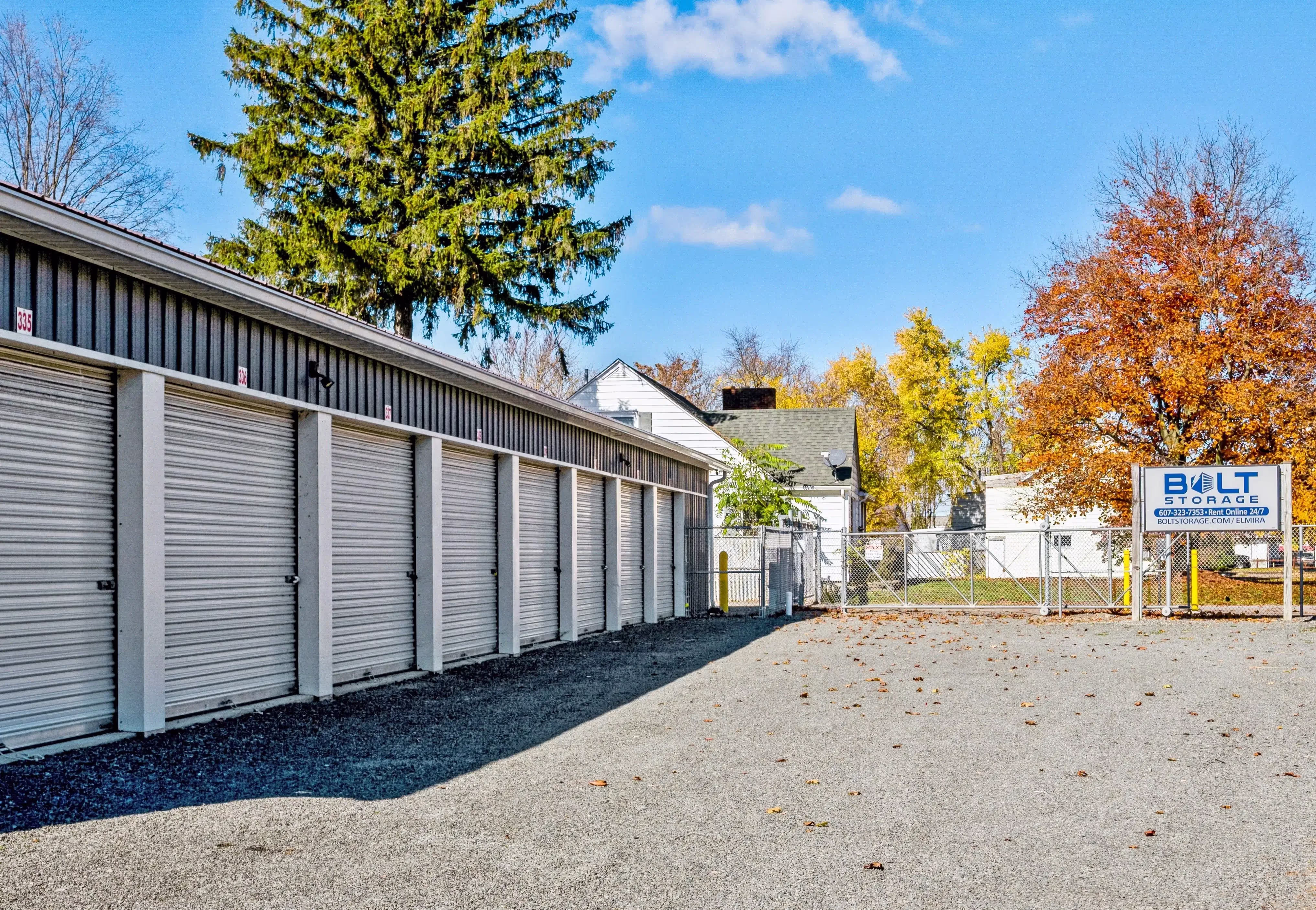 Row of drive up storage units with white roll up doors and gravel driveway at our Elmira NY facility