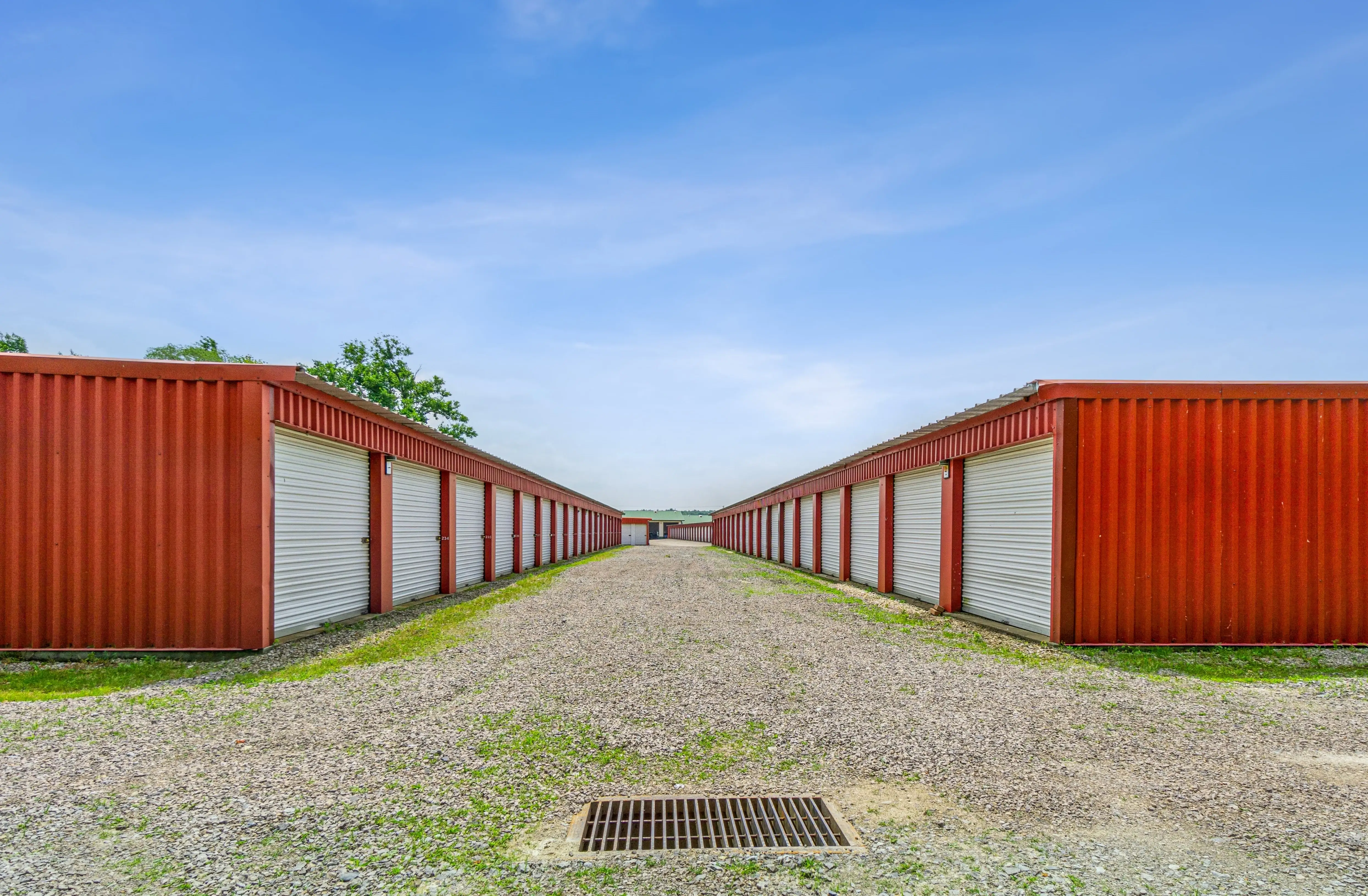 Long stretch of red storage units forming a corridor with gravel driveways on both sides at our Fairview PA location