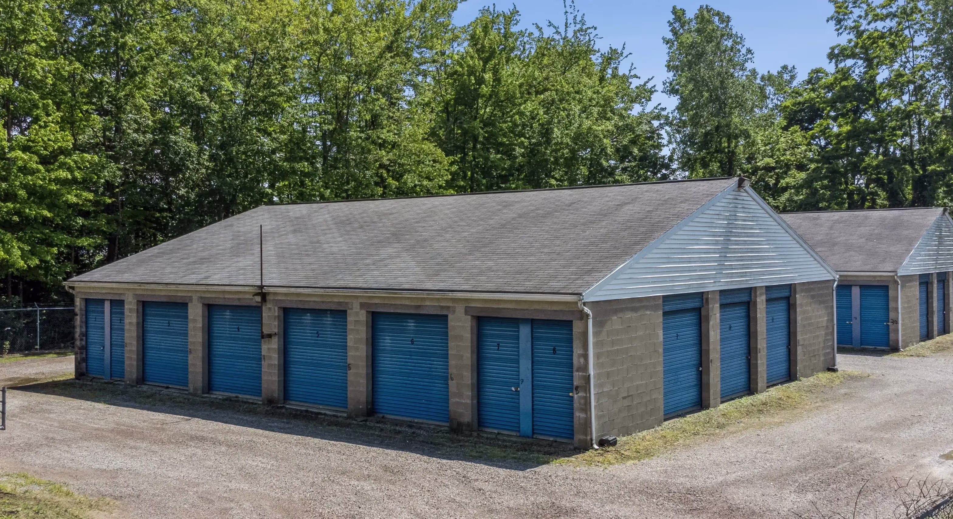 Angled view of drive up storage buildings with blue doors on gravel driveway in Fairview PA